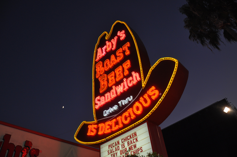 Vintage Arby's neon cowboy hat sign glowing at night