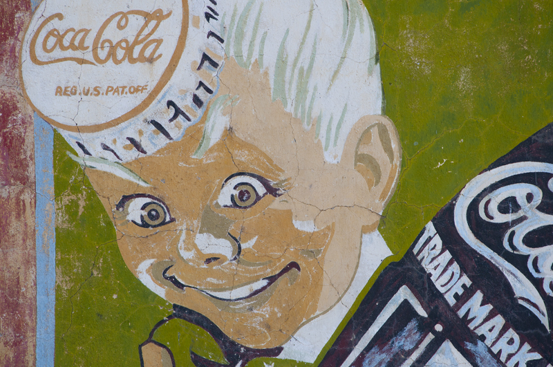 Old vintage Coke sign depicting a boy holding a bottle