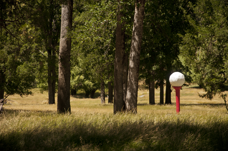 Giant golf tee sculpture standing in open landscape